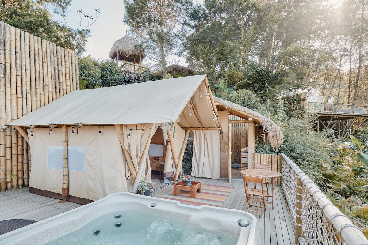 A cozy outdoor area with a hot tub, a wooden deck, and a tented structure.