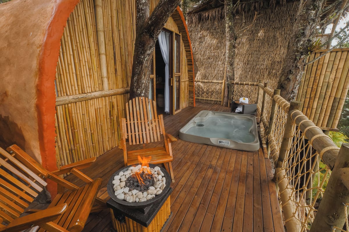 A wooden deck with a hot tub, a fire pit, and a chair.