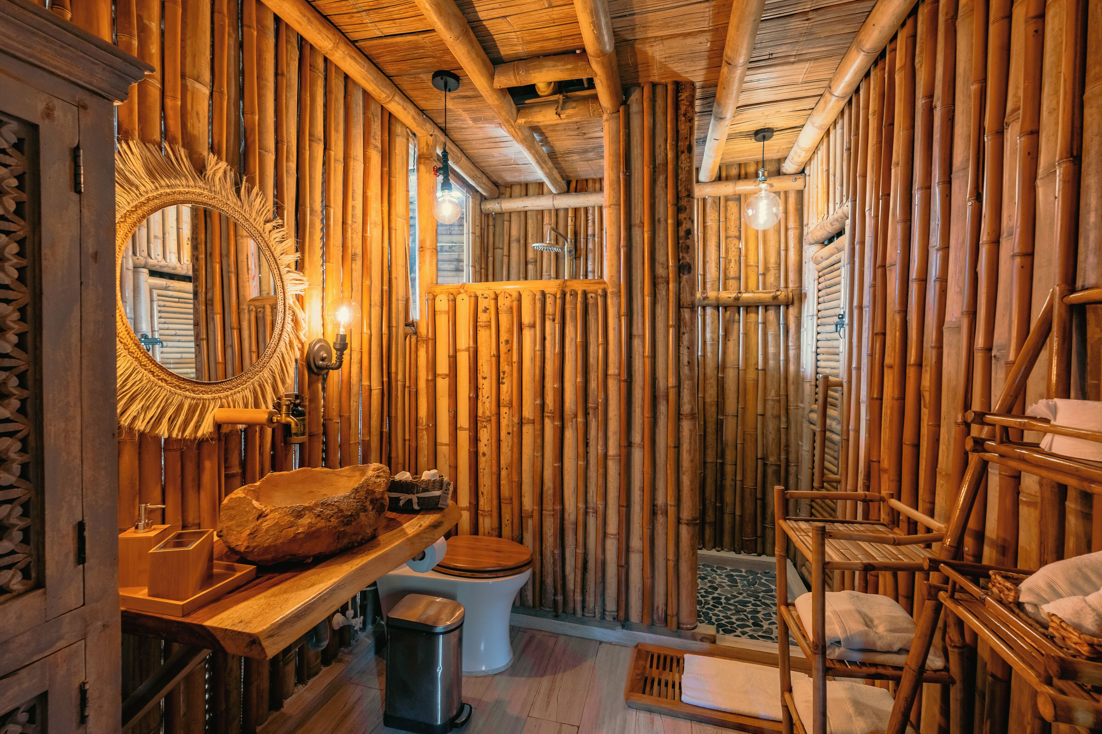 A rustic bathroom with a wooden interior, a large mirror, a wooden bench, and a toilet.