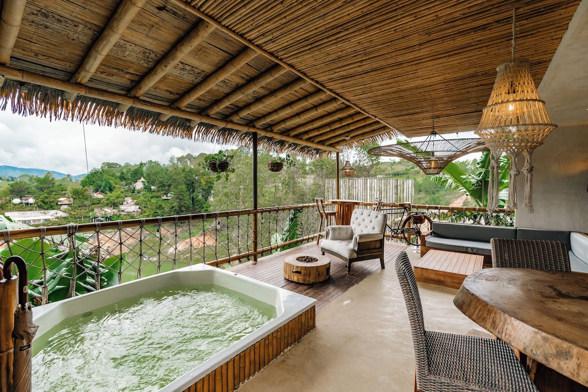 A wooden deck with a hot tub, wicker furniture, and hanging planters.