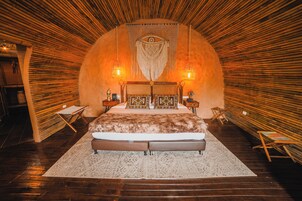 Un dormitorio con una cama grande, paredes de madera y dos lámparas fijadas a la pared.