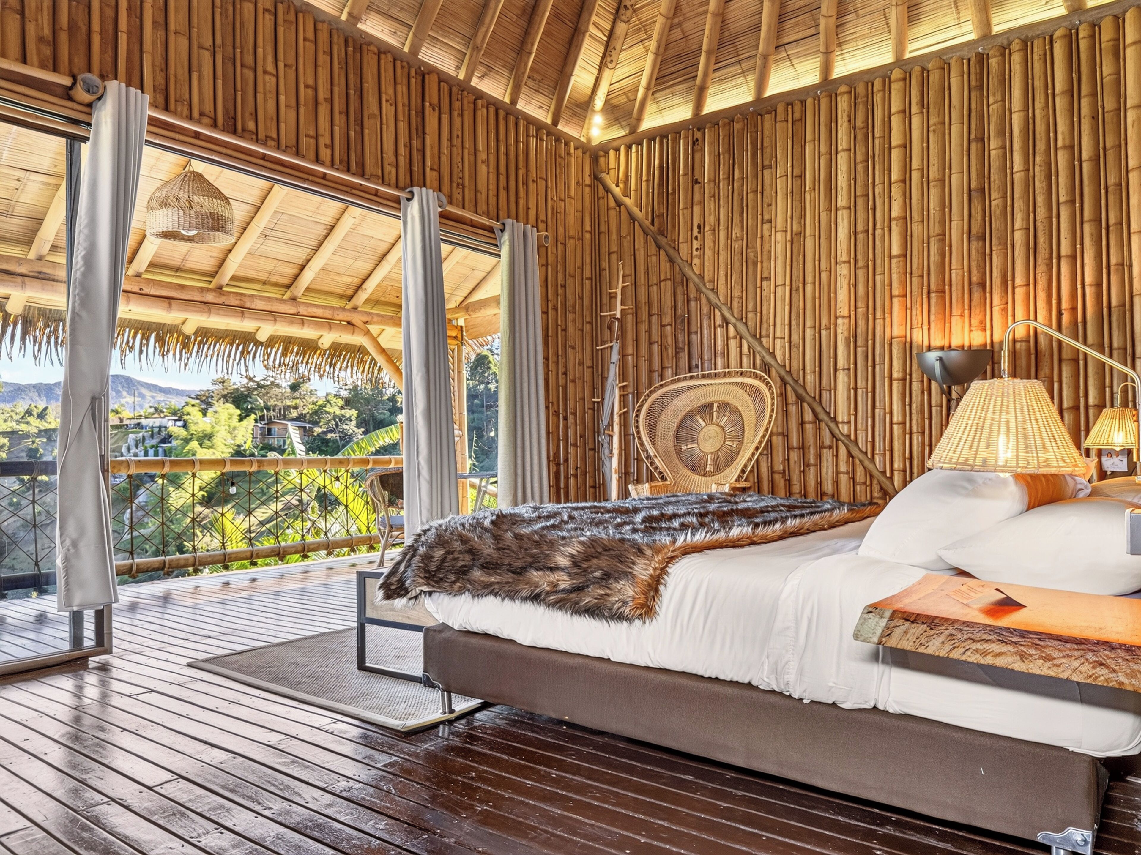 Una habitación con cama, silla, lámpara y vista a zonas verdes.