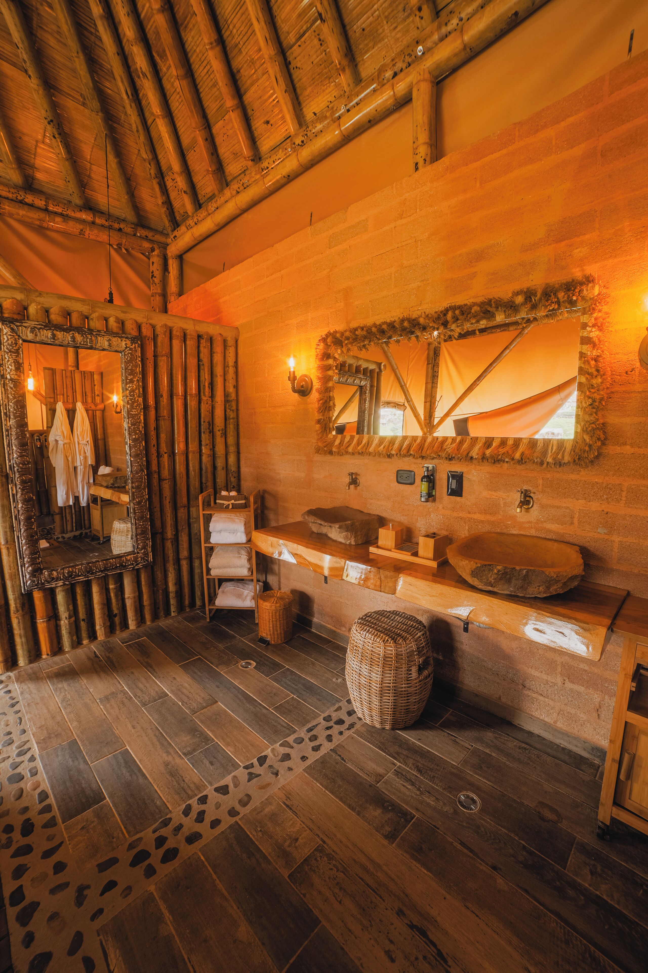 A rustic bathroom with a wooden vanity, a large mirror, and a stone sink.