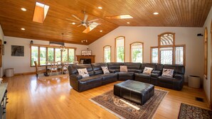 A spacious living room with a large sectional sofa, a dining area with a table and chairs, and a ceiling fan. - NEW: Kids Lifted PlayHouse! Pool, Hot Tub, SportCourt. Minutes From South Haven. (Bangor)