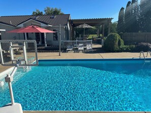 Ein Schwimmbecken mit Basketballkorb, Liegestühlen und einer überdachten Terrasse.