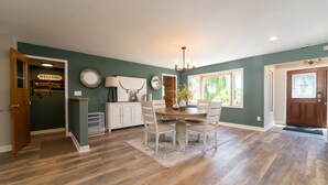 A dining area with a wooden table and chairs, a chandelier, and a welcome sign. - NEW: Kids Lifted PlayHouse! Pool, Hot Tub, SportCourt. Minutes From South Haven. (Bangor)