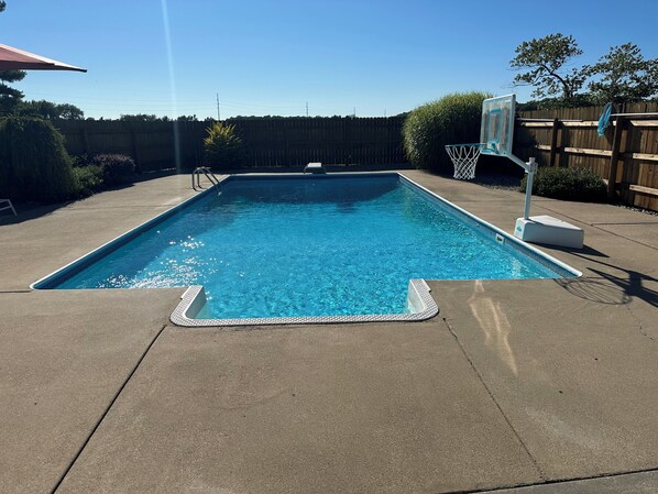 Ein rechteckiger Swimmingpool mit glasklarer blauer Wasseroberfläche, umgeben von einer Betonplattform.