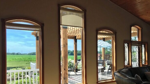 A room with large windows, a wooden ceiling, and a view of a garden and outdoor seating area. - NEW: Kids Lifted PlayHouse! Pool, Hot Tub, SportCourt. Minutes From South Haven. (Bangor)