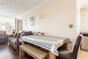 A modern living room with a dining table, sofas, and a kitchen area. - Sea Spirit- Short Walk to Alum Chine Beach (Bournemouth)
