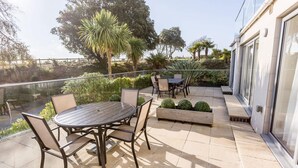 Une terrasse extérieure avec une table ronde et des chaises, entourée de verdure et offrant une vue sur le paysage.