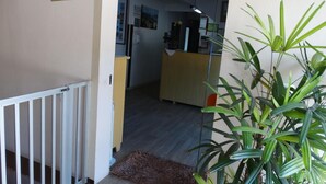 A hallway leading to a reception area with a desk, a plant, and a sign labeled "GARAGEM". - Hotel Mirante (Barra Velha)