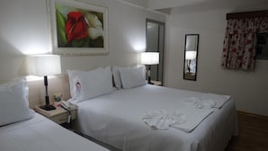 A hotel room with two single beds, a bedside table with a lamp, a phone, and a painting of flowers on the wall. - Hotel Mirante (Barra Velha)
