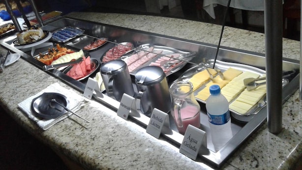 A buffet with various food options and labeled containers for water, milk, and juice. - Hotel Mirante (Barra Velha)