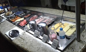 Un bufé con diversas opciones de comida y recipientes identificados para agua, leche y jugo.
