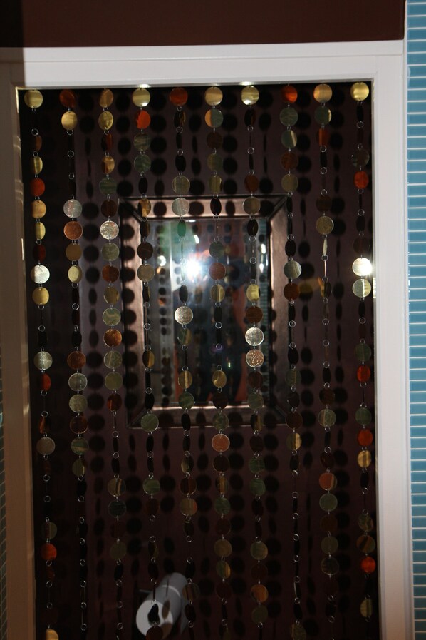 Une porte ornée d’un miroir décoratif et d’un motif circulaire composé de disques réfléchissants.