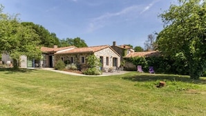 A stone house with a tiled roof, surrounded by a well-maintained lawn and trees. - La Maison des Landes (Gorges)