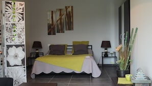 A modern bedroom with a bed, bedside tables, a desk, and a potted plant. - La Maison des Landes (Gorges)