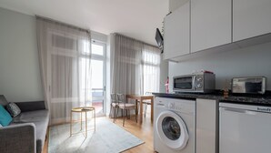 Een modern appartement met een bank, eettafel, stoelen, een wasmachine, een magnetron en een vaatwasser.