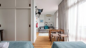 Een moderne hotelkamer met twee bedden, een eettafel en een bank.