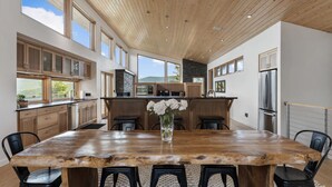 Una cocina amplia con armarios de madera, una isla grande y una zona de comedor con mesa rústica.