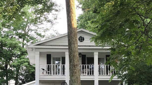 A two-story white house with a balcony, a front porch, and a well-maintained lawn.