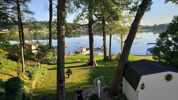 A lakeside property with a dock, grassy areas, and a white building with a sloped roof.