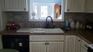 A kitchen with white cabinetry, a window above the sink, and a dishwasher to the left.