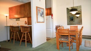 Un comedor con sillas de madera y una mesa, un refrigerador blanco y un armario de madera.