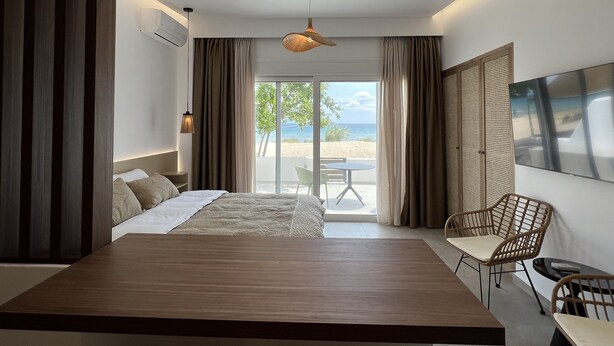 Une chambre d’hôtel moderne dotée d’un grand lit, d’un coin repas et offrant une vue sur la plage.