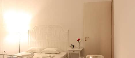 Een keurig opgemaakt slaapkamer met een bed, nachtkastje en een tafeltje met een kaars.