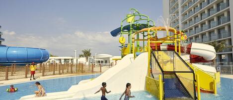 A water park area with a large pool, slides, and a multi-level water play structure.