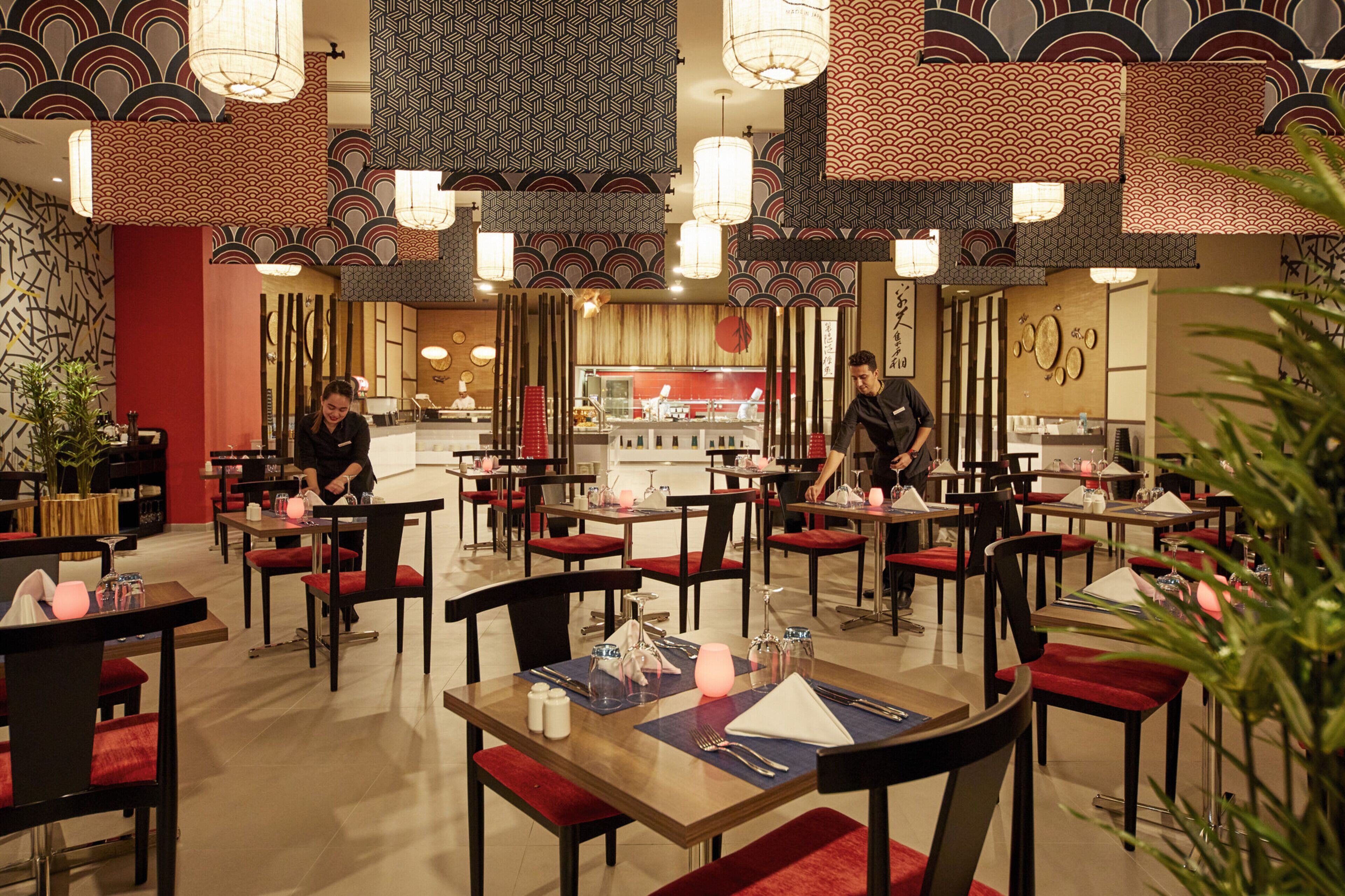 A restaurant with tables set for dining, a bar area, and a counter.