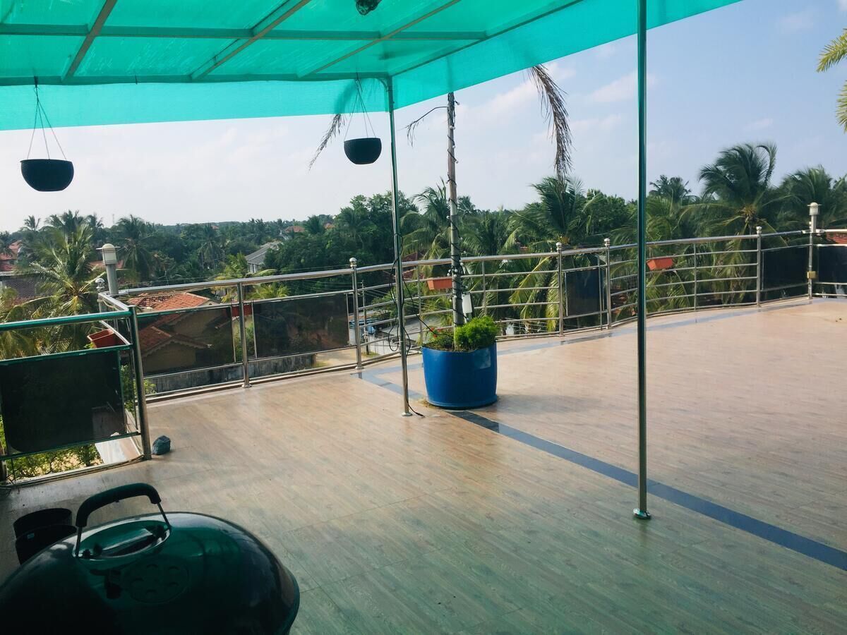 Une terrasse sur le toit, dotée d’un auvent bleu, d’un grand pot de fleurs et d’une rambarde en métal.