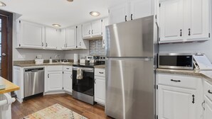 Een moderne keuken met witte kasten, roestvrijstalen apparatuur en een patroonrijk vloerkleed.