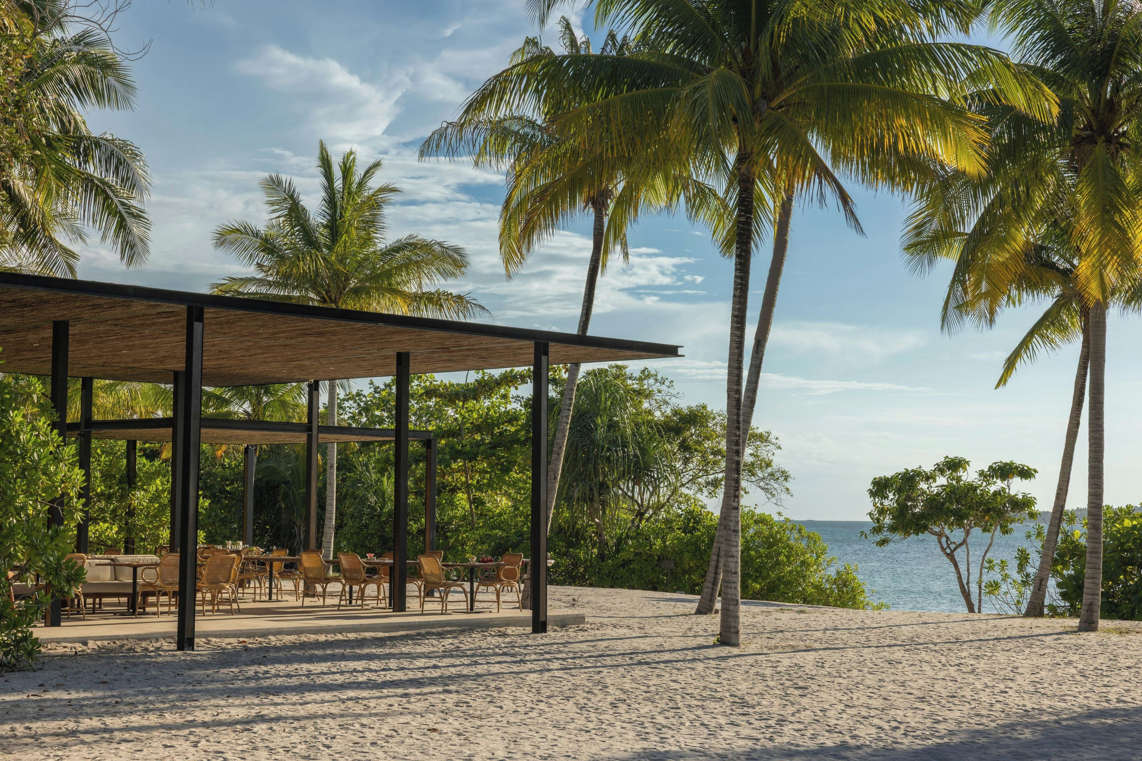 A beachside restaurant with outdoor seating and a view of the sea.