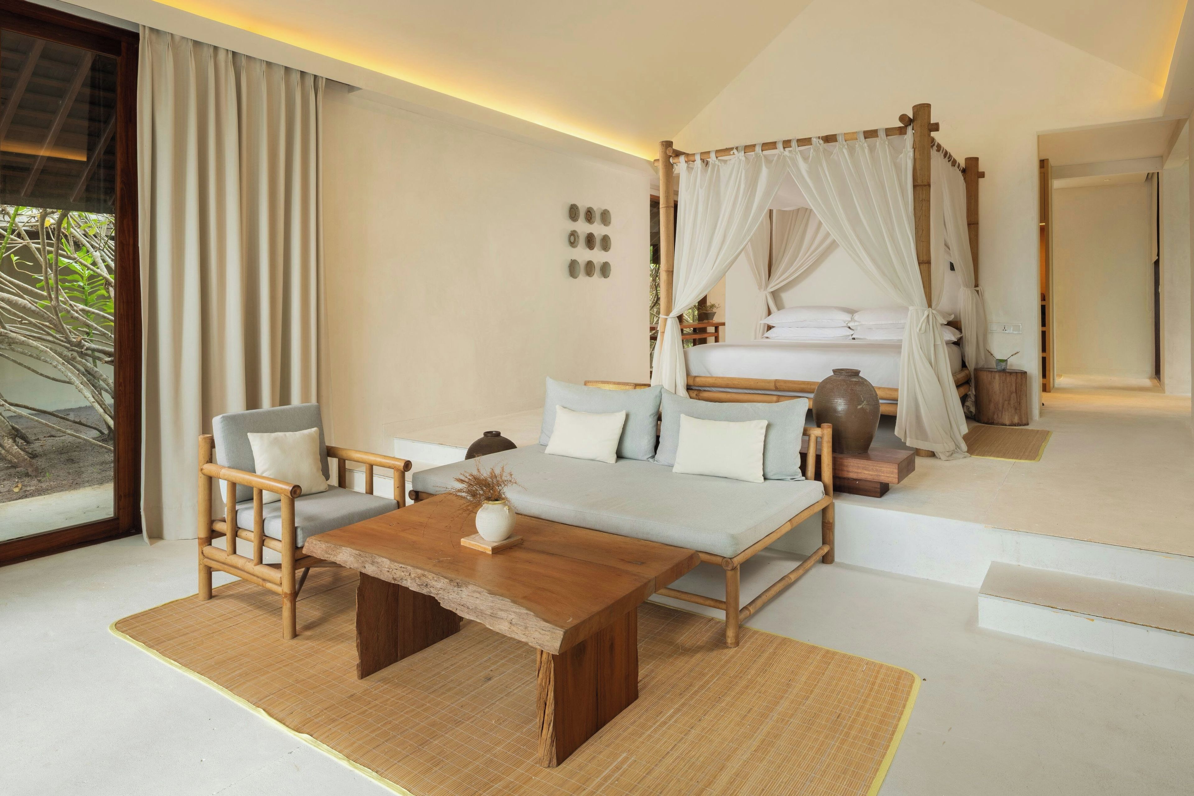 Een slaapkamer met een bed, een zithoek met een tafel en een groot raam.