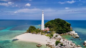 A lighthouse on a small island with clear turquoise waters and a sandy beach. - Sheraton Belitung Resort (Tanjung Pandan)