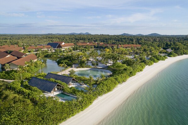 A resort with multiple buildings, a beach, and a lake.