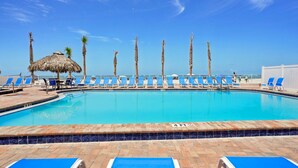 Una piscina con sillas reclinables azules y palmeras.