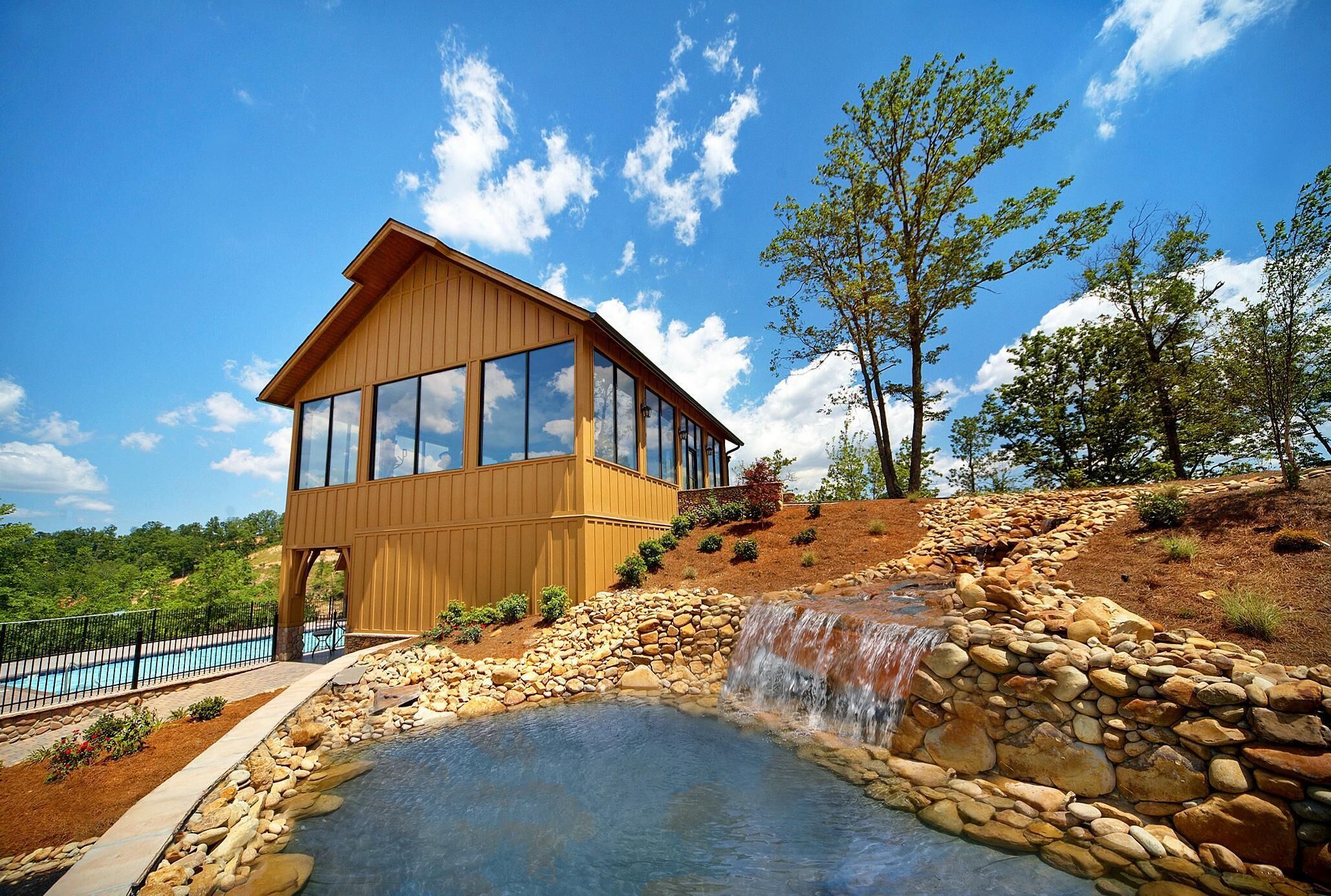Una casa moderna de madera con ventanas amplias, una piscina y una cascada.