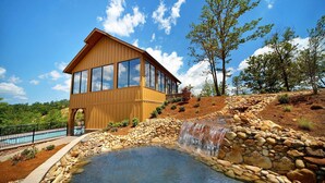 A modern wooden house with large windows, a swimming pool, and a waterfall. - Tennessee Treasure #232 (Sevierville)