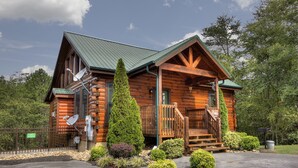 A log cabin with a green roof, a porch, and a staircase leading to the entrance. - Serenity Now #370 (Pigeon Forge)