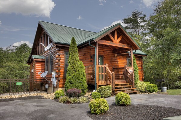 A log cabin with a green roof, a porch, and a staircase leading to the entrance. - Serenity Now #370 (Pigeon Forge)