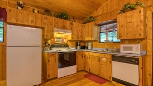 A wooden cabin-style kitchen with a refrigerator, stove, microwave, and dishwasher. - Secret Hideaway #195 by Aunt Bug's Cabin Rentals (Sevierville)