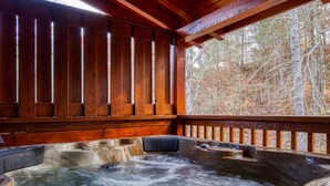 Un espace avec un bain à remous, doté de rampes en bois et offrant une vue sur une zone boisée.