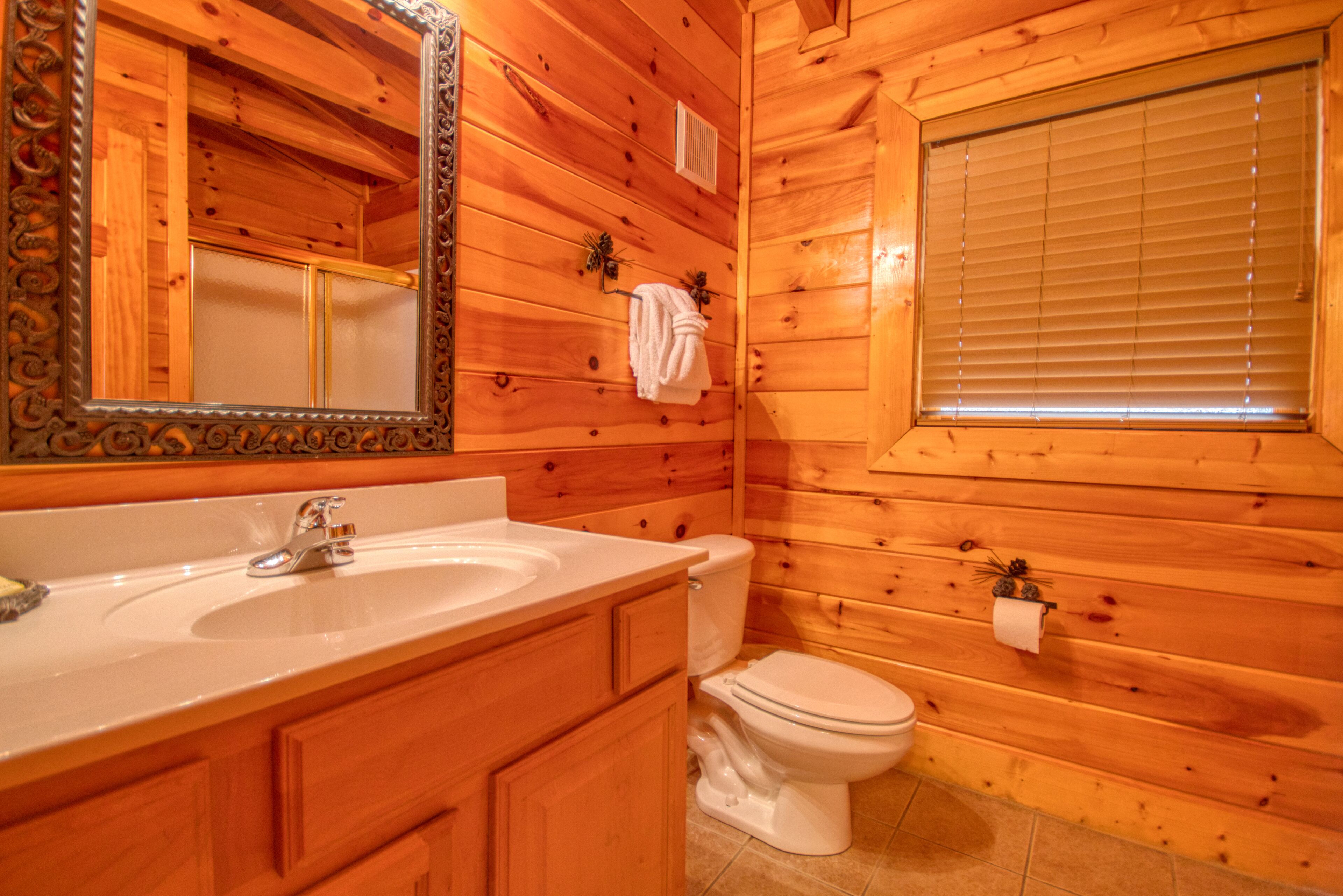 Ein Badezimmer einer Holzhütte mit einem Holzanrichte, Waschbecken und Toilette.