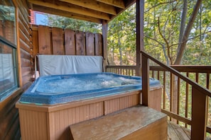 A hot tub in a wooden cabin with a wooden deck and a view of trees. - Smoky Mountain Getaway #435 (Sevierville)