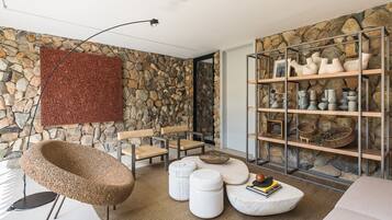 A modern living room with a stone wall, a round seating area, and a shelf with decorative items.