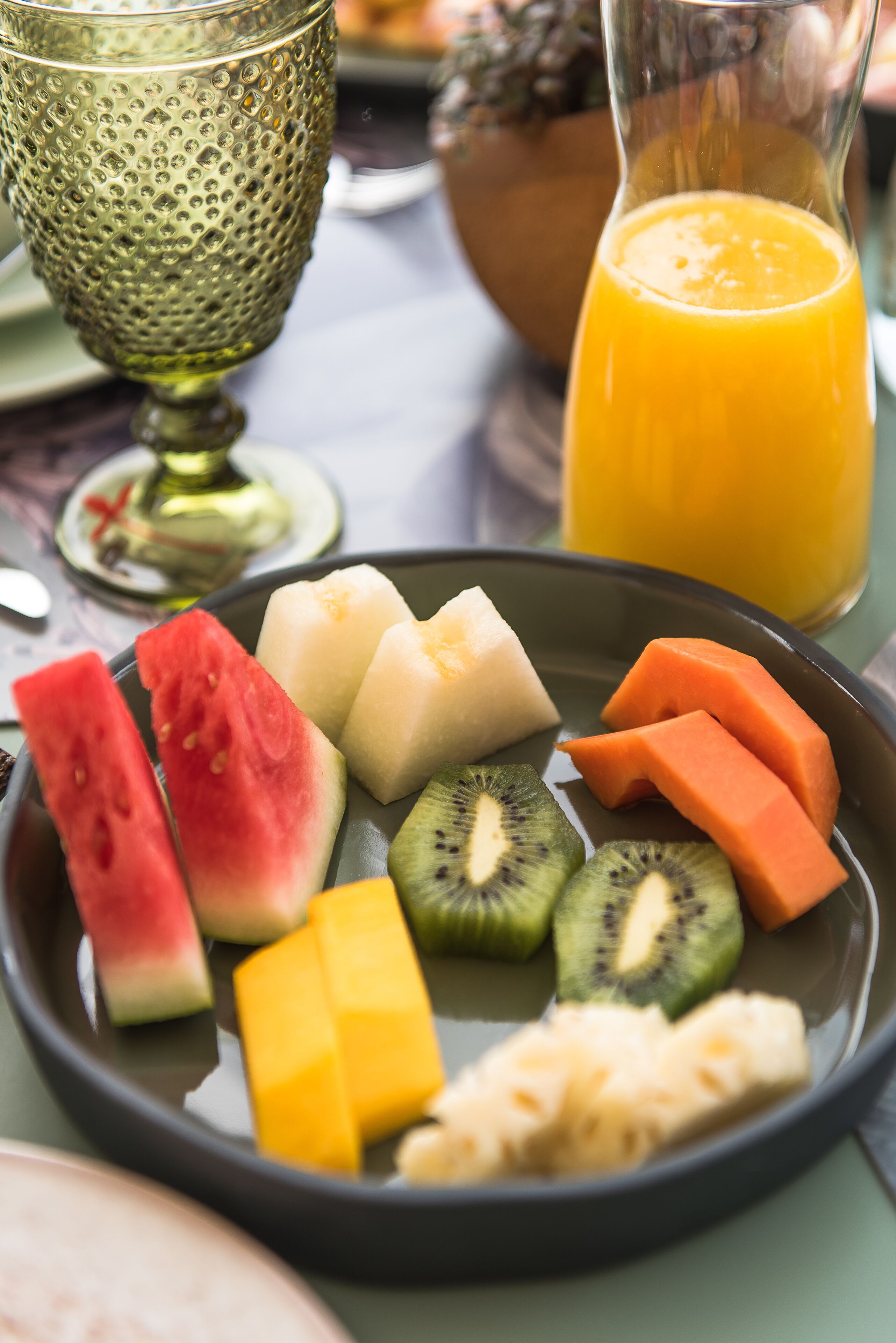 A breakfast plate with various fruits and a glass of orange juice.