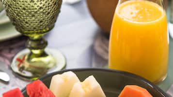 A breakfast plate with various fruits and a glass of orange juice.